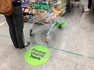 Person with shopping trolley full of groceries standing in line in supermarket