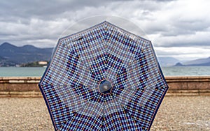 a person showing a rounded shaped checked fabric umbrella on a rainy day