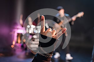 Person showing sign of the horns while rock band playing