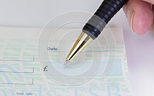 Person signing check with pen in cheque book