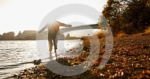 Person, silhouette and river with walk, sunrise and nature in morning with freedom, game and balance. Woman, girl and