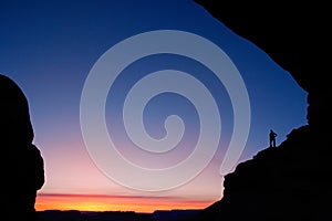 Person silhouetted at North Window Arch at sunrise, Arches National Park, Utah, USA