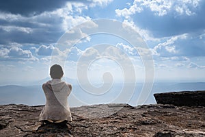 A person sitting on rocky mountain looking out at scenic natural view