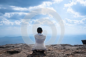 A person sitting on rocky mountain looking out at scenic natural view