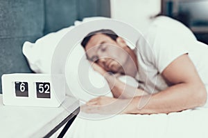 Person Sleeps Near Alarm in Bed With White Linens