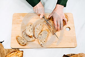 Person Slicing Artisan Bread on Cutting Board. Artisan homemade bread free from additives and preservatives