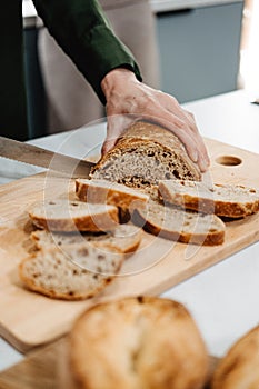 Person Slicing Artisan Bread on Cutting Board. Artisan homemade bread free from additives and preservatives