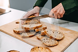 Person Slicing Artisan Bread on Cutting Board. Artisan homemade bread free from additives and preservatives