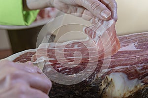 Person slicing ham slices with a knife