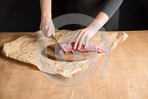 A person slicing pork tenderloin for making a meal