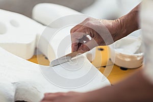 Person smoothing with cream the surface of a polystyrene figure with a spatula photo