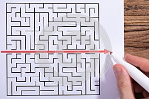 Person Solving Maze Puzzle With Red Marker