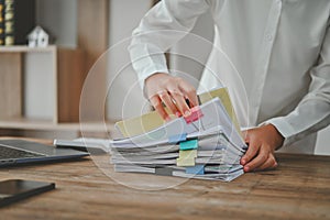 A person is sorting through a stack of papers on a desk