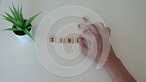 A person spelling out soulful in wooden letter tiles