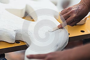 Person spreading cream to smooth a polystyrene figure using a spatula photo
