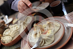 Person sprinkles with pepper Khinkali