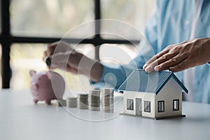 Person with stack of coins and piggy bank, saving money concept for future use.