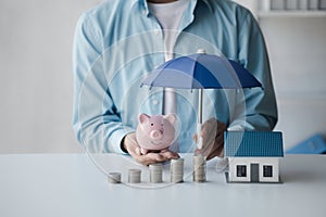 Person with stack of coins and piggy bank, saving money concept for future use.