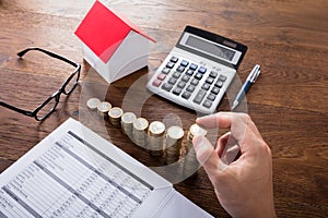 Person Stacking Coins On Wooden Desk