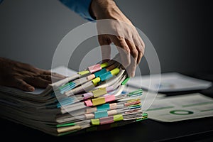 Person with stacks of company financial report papers in office, company employee picking up papers on table to use for