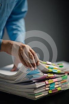 Person with stacks of company financial report papers in office, company employee picking up papers on table to use for