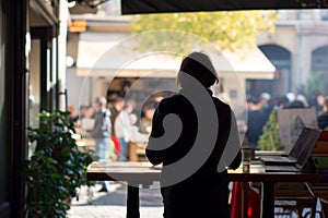 person at standing desk watches bustling outdoor caf