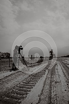 person standing on a dirt road with camera set up for recording