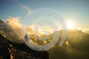 A Person Standing on the Mountain with Clouds During Sunset/Sunr