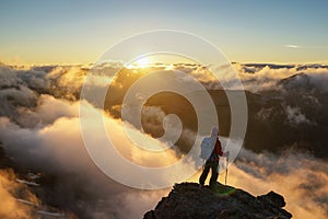 A Person Standing on the Mountain with Clouds During Sunset/Sunr