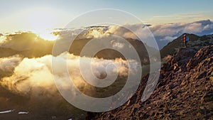 A Person Standing on the Mountain with Clouds During Sunset/Sunr