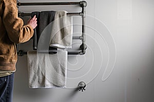 person standing near a wallmounted towel rack made of iron pipes