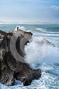 Person standing on a rocky outcrop fishing in Baleal Island, Portugal