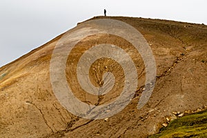 Person standing on the top of a sandy hill