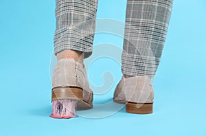 Person stepping into chewing gum on light blue background, closeup