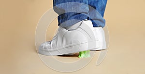 Person stepping into chewing gum on light brown background, closeup