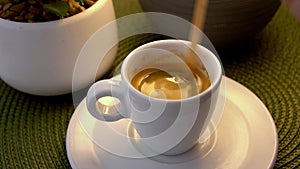 Person stirring sugar in coffee espresso with wooden stick spoon in white cup. Close-up