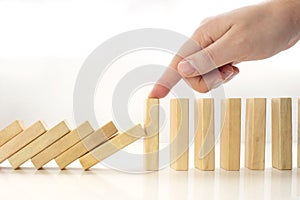 A person stopping wooden pieces of a domino effect.