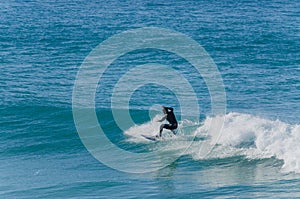 Person surfing a wave in a blue winter sea