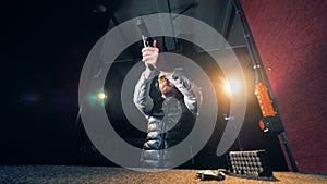 A person takes a gun and aims at a shooting range, bottom view.