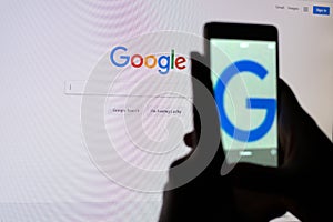 A person takes a picture of the monitor screen with a Google search string.