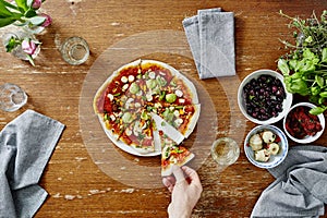 Person taking first slice out of organic delicious pizza