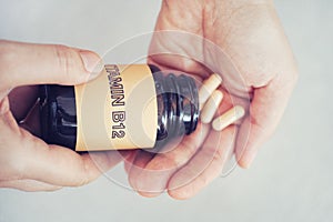 Person taking out Vitamin B12 pills out of bottle photo
