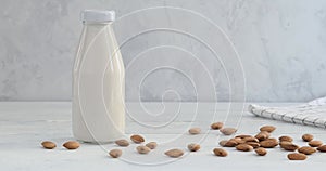 Person tasting almond milk, hand taking a glass with alternative milk drink made of almond nuts, kitchen table, bottle