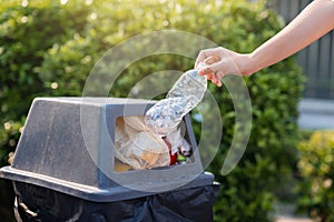 person is throwing away a plastic bottle in a trash can