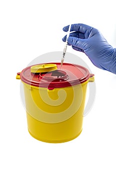 A person throwing away a syringe into a medical waste container