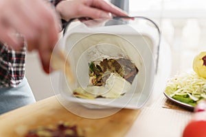 Person throwing organic food waste in a compost bin. Woman recycling compostable leftovers in a bokashi container with ferment