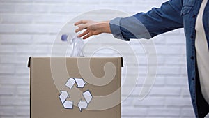 Person throwing plastic bottles into trash bin, sorting non-degradable waste