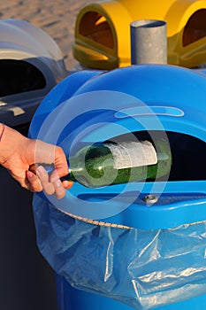 Person throws the glass bottle into the differentiated collection basket