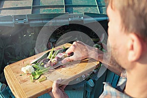 Person throws kitchen food waste into compost heap to make organic fertilizer. Composting - eco-friendly recycling technology.