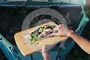 Person throws organic waste from his kitchen into compost heap. Composting - eco-friendly recycling technology. Kitchen waste